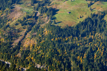 Aerial view of the mountainside at the morning with the autumn forest and old barns in...