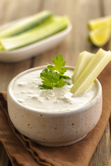 Blue cheese sauce in a portion with fresh vegetables and lime and green parsley. Wooden background and natural napkin. Close up and vertical view.