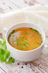 Cooked hot bone broth with spices and fresh herbs. Medical dietary broth and superfood. For...