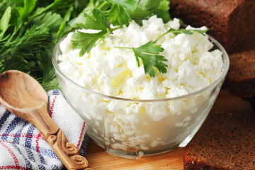 A bowl with cottage cheese, a bunch of green and rye bread
