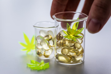 Frau nimmt Pillen, Tabletten,  Kapseln mit Cannabis Marihuana Hanf und CBD in Labor Becherglas gegen Schmerzen zur Therapie 