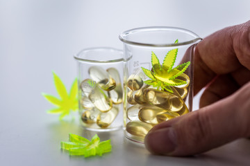 Frau nimmt Pillen, Tabletten,  Kapseln mit Cannabis Marihuana Hanf und CBD in Labor Becherglas gegen Schmerzen zur Therapie 