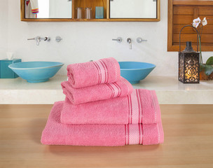 FOUR PIECE OF PINK COTTON TOWEL SET ON BROWN SURFACE