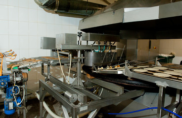Pancakes are fried on the conveyor in factory