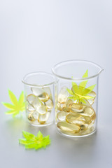 Pillen, Tabletten, Kapseln mit Cannabis Marihuana Hanf und CBD in Labor Becherglas gegen Schmerzen zur Therapie als Medizin 