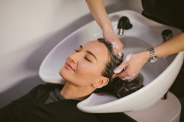 Hairdresser washing hair to a client, beauty and relaxation concept