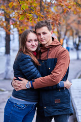 Fototapeta premium Lovers. A loving couple walks around the city. A loving couple holding hands. Couple hug and kiss. Romantic walk of lovers. Romantic walk by the spring street. Portrait photo of lovers.