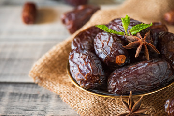 Ramadan food and drinks concept. Dates fruit and green Mint leaves in a bowl on wooden table background.