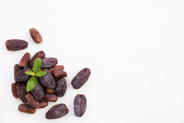 Ramadan food and drinks concept. Dates fruit and green Mint leaves in a bowl on a white wooden table background. Top view, Flat lay.
