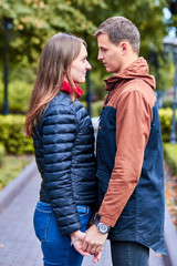 Fototapeta premium Lovers. A loving couple walks around the city. A loving couple holding hands. Couple hug and kiss. Romantic walk of lovers. Romantic walk by the spring street. Portrait photo of lovers.