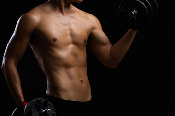 Fototapeta na wymiar Closeup of a strength fitness body with dumbbell and sweat. Fit young man with beautiful torso. Beginner Bodybuilder and muscular body concept.