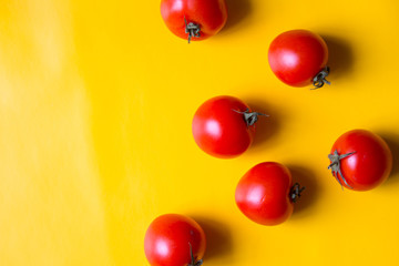 Ripe red tomatoes with green leaves isolated on yellow background. Top view.