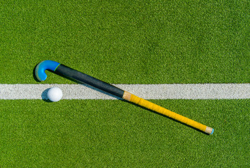 Field hockey stick and ball on green grass