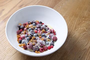 Frozen fruits with granola and yogurt, healthy fruit breakfast.