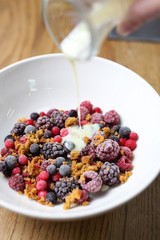 Frozen fruits with granola and yogurt, healthy fruit breakfast.