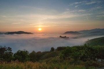 sunrise at Phu Huay Isan View Point, view of the hill around with sea of mist above Mekong river with blue sky background, Ban Muang, Sang Khom District, Nong Khai, Thailand.