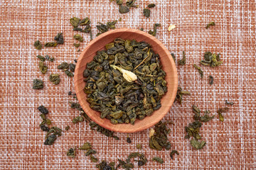 The composition of natural tea with jasmine. A macro photo of tea petals on a wooden spoon with...