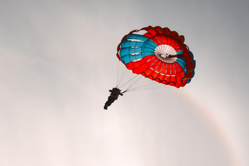 Silhouette of a paratrooper with a bright round parachute in the sky close-up.