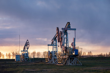 Fototapeta na wymiar Oil well at sunset. Oil production by a rocker at sunset. Rocking machine for oil