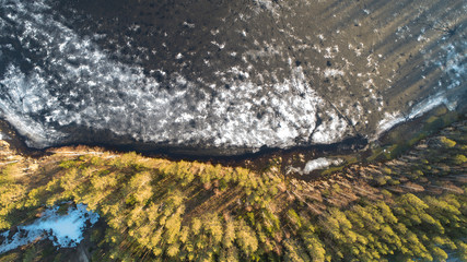 Aerial view on river with melting ice, sunny spring weather with snow.