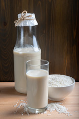 Glass of Rice milk and organic rice seeds on wooden background, Alternative Milk