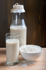 Glass of Rice milk and organic rice seeds on wooden background, Alternative Milk