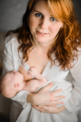Breast-feeding. Red-haired beautiful mother breastfeeds a newborn baby. Natural looking photos