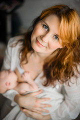 Breast-feeding. Red-haired beautiful mother breastfeeds a newborn baby. Natural looking photos