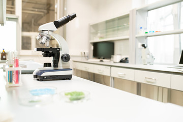Close-up of laboratory workplace with microscope and glassware used for researching substances and liquids