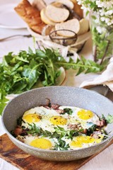 fried eggs with bacon and dandelion leaves (dish with dandelion).  spring breakfast with first greens. dandelion-a useful edible flower, rich in vitamins.