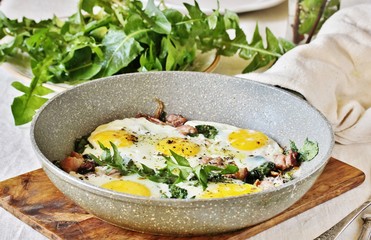 fried eggs with bacon and dandelion leaves (dish with dandelion).  spring breakfast with first greens. dandelion-a useful edible flower, rich in vitamins.