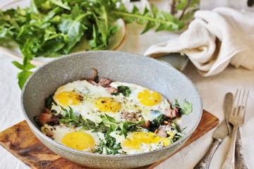 fried eggs with bacon and dandelion leaves (dish with dandelion).  spring breakfast with first greens. dandelion-a useful edible flower, rich in vitamins.