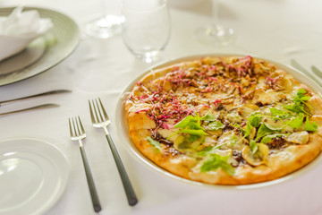 Pizza with mozzarella cheese, fresh tomato and pesto sauce on elegant table set up