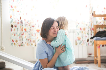 cute girl hugs mom, daughter toddler blonde