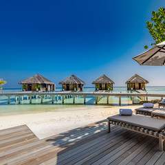 Maldives beach with luxurious water villas and loungers beautiful tropical scene. Luxury summer travel destination background concept. Beach mood for summer vacation or holiday  design