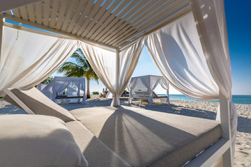 Inspirational beach mood scene with white canopy and curtain for luxury summer relaxation concept. Blue sky with white sand for sunny beach landscape background and summer vacation or holiday design 