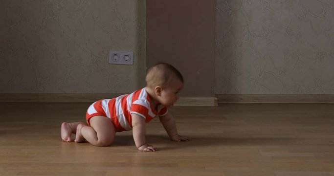 Cute and funny smiling baby boy crawling on floor at living room