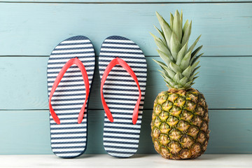 Ripe fruit pineapple and beach accessories, flip flops on the blue wooden background. summer. space for text
