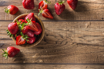 Juicy washed strawberries in wooden bowl on kitchen table