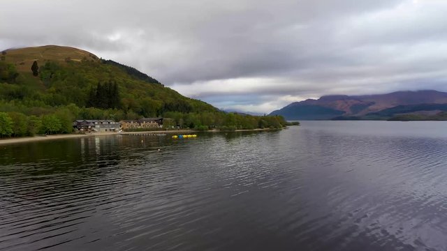 Aerial depiction of the beautiful village of Luss on the banks of Loch Lomond, featuring The Lodge on the Lake and Ben Lomond in the background.