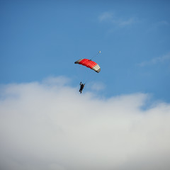 Bright parachute against a blue sky with clouds. Square image.