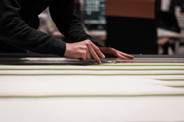 Print and fashion industry working together. Close up of a cobbler assembling a dress with black and colored printed fabrics. Cutting prcoess before stitching. Artisan and fashion concept.