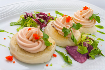 tartlets with red caviar, butter, sprigs of parsley and lettuce on a white plate on a white background