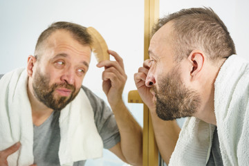Man using comb in bathroom