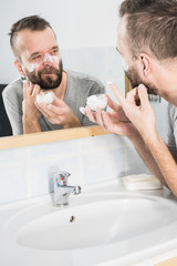 Man applying moisturizer cream in bathroom