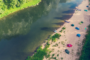 Camping tents on the beach. Tourists rafting on the river on a halt