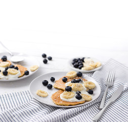 Homemade oatmeal pancakes with yogurt, fresh blueberry and banana at white wooden background.
