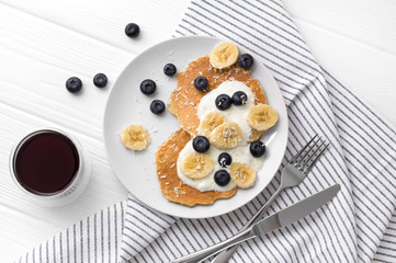 Homemade oatmeal pancakes with yogurt, fresh blueberry and banana at white wooden background.