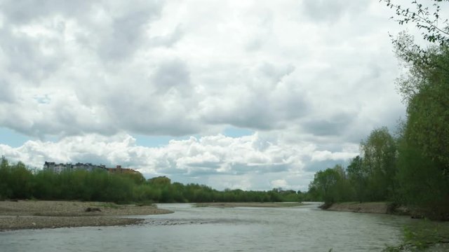 Watercourse of the mountain river after heavy rains against the background of the blue sky and white clouds, background, time lapse