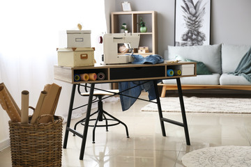 Sewing machine with accessories on tailor's workplace in atelier
